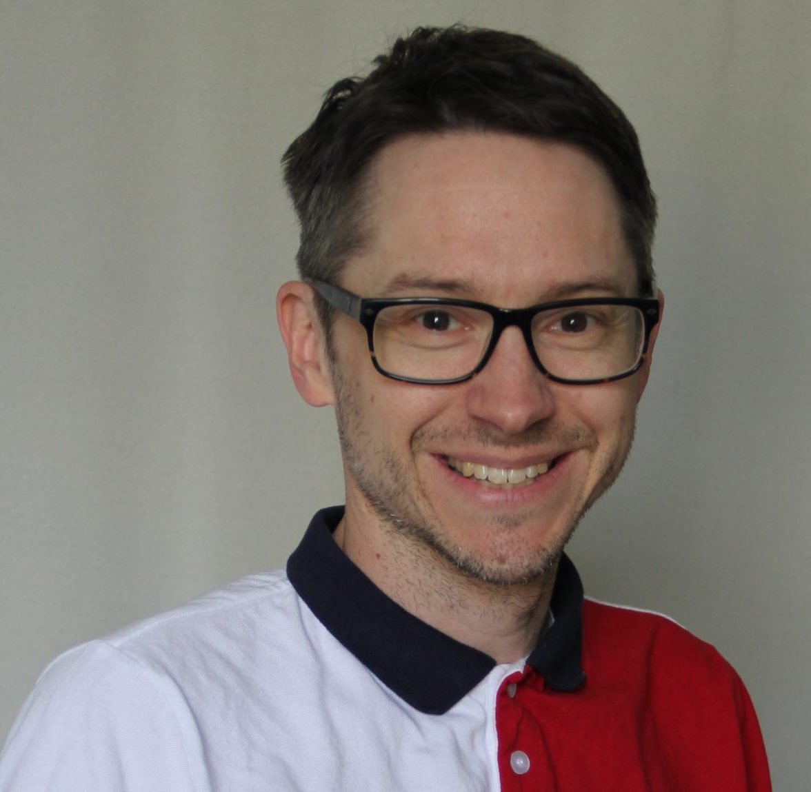 Man in a white, red, navy blue t-shirt with glasses