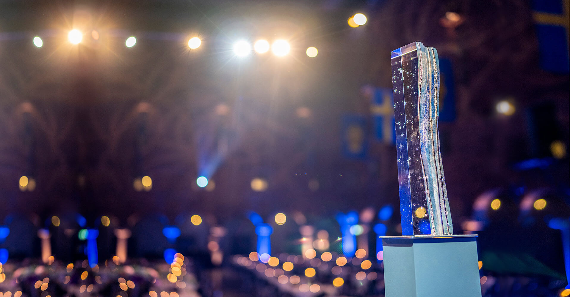 Statue of Stockholm Water Prize award with yellow and blue light halos in the background