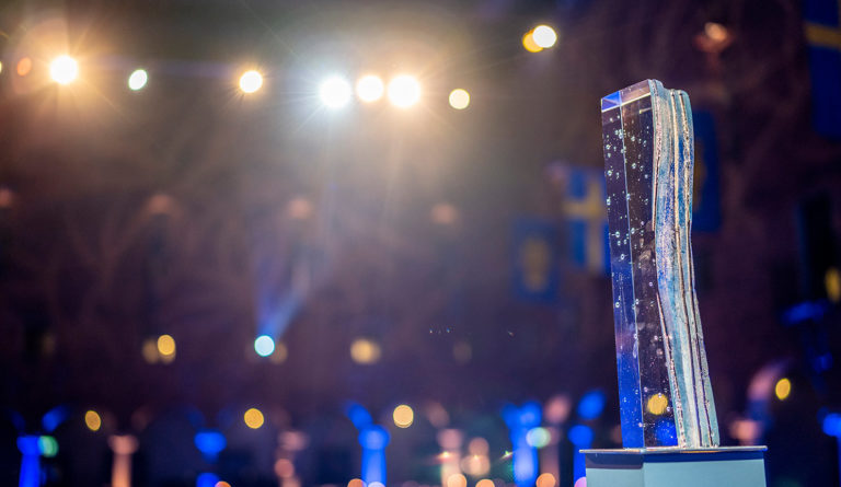 Stockholm Water Prize statue in front of the Stockholm City hall banquet room, with blue and yellow lights creating an artistic blur effect in the background