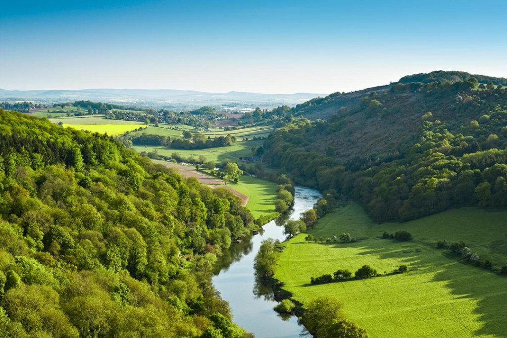 Aerial view of a river flowing between mountains down to a fertile valley