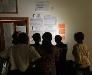 Participants, with their backs facing the camera, at a workshop on water, sanitation and hygiene read notes pasted to a wall in Central African Republic.