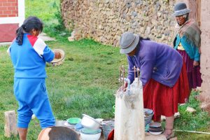 three women getting water from faucet