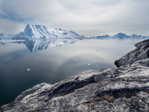 Glacier floating on the horizon. A block of grey rock in the foreground.