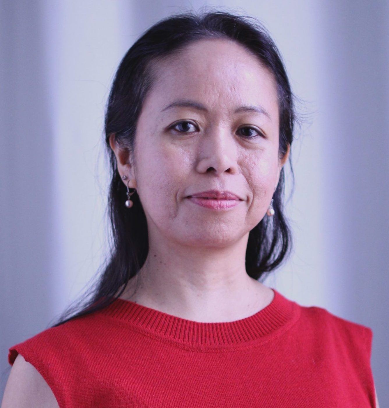 Woman facing camera wearing red sleeveless shirt