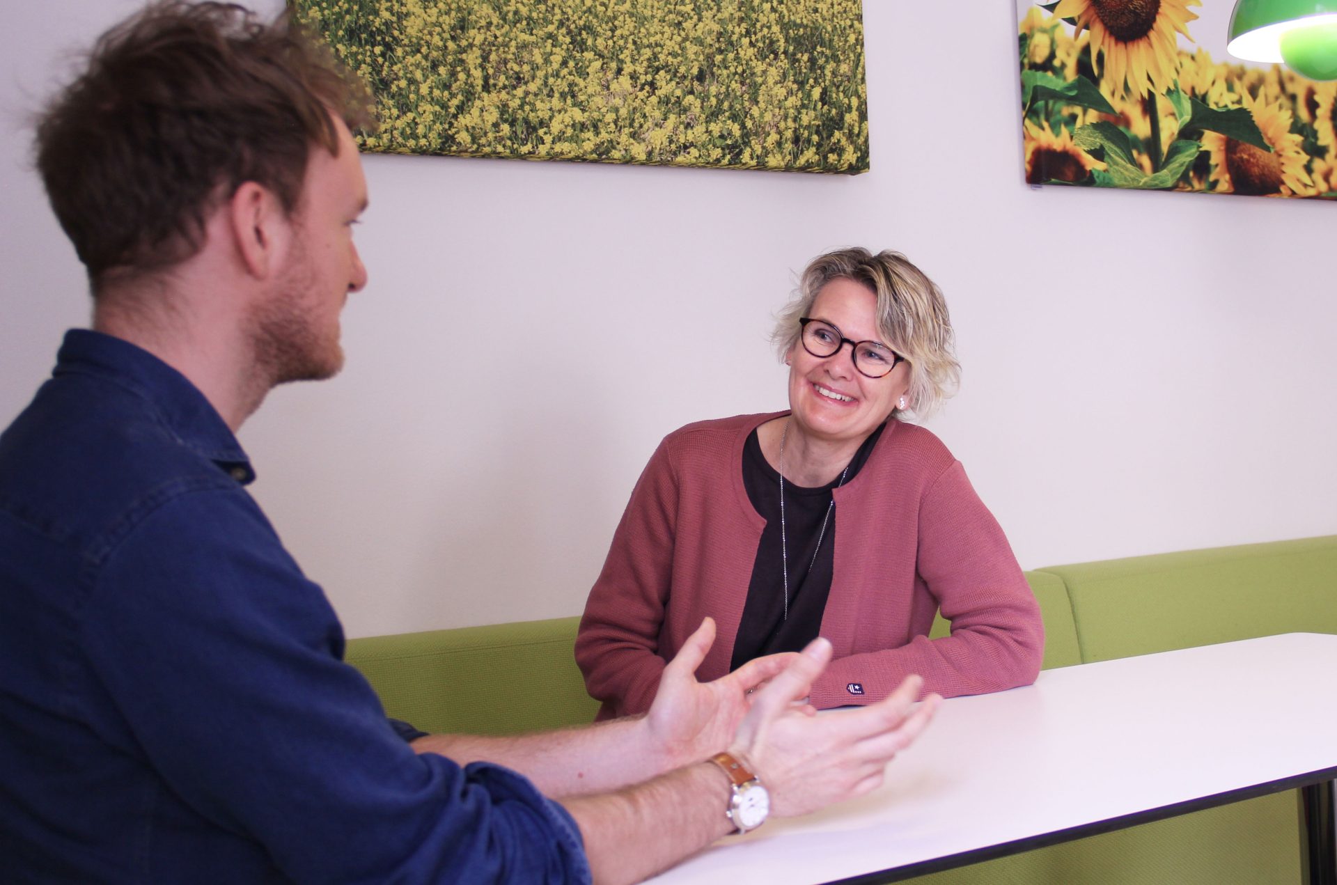 Jakob Schabus and Maria Sköld sitting at a table facing each other and discussing