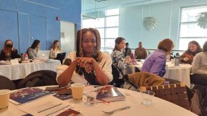 Woman sitting with folded hands in a cafeteria / coworking space