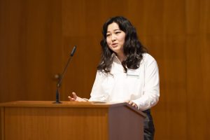 Woman with a white shirt, speaking into a mic